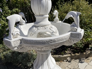 Detailansicht der Delfine und des verzierten Beckenrands am Betonbrunnen