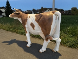 grosse braun-weisse gartenfigur kuh von hinten rechts betrachtet