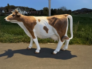 lebensgrosse kuhfigur als gartendeko im weiten seitenprofil