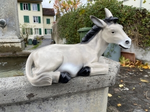 Graue Eselfigur liegend von der rechten Seite