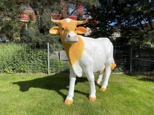Weiss-beige Deko Kuh von vorne im Garten